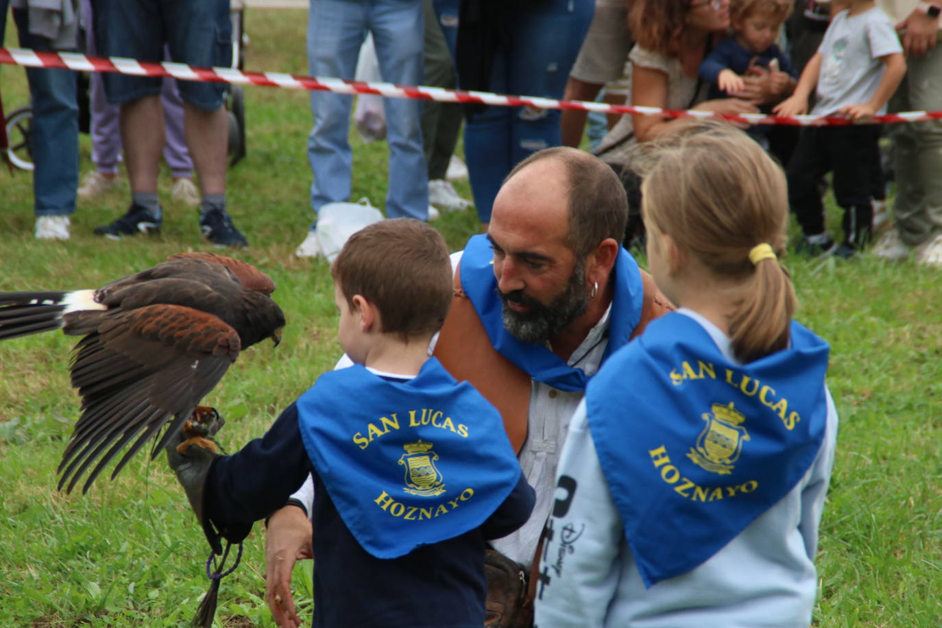 Dos niños con el pañuelo de las fiestas de San Lucas conocen de cerca un águila. 